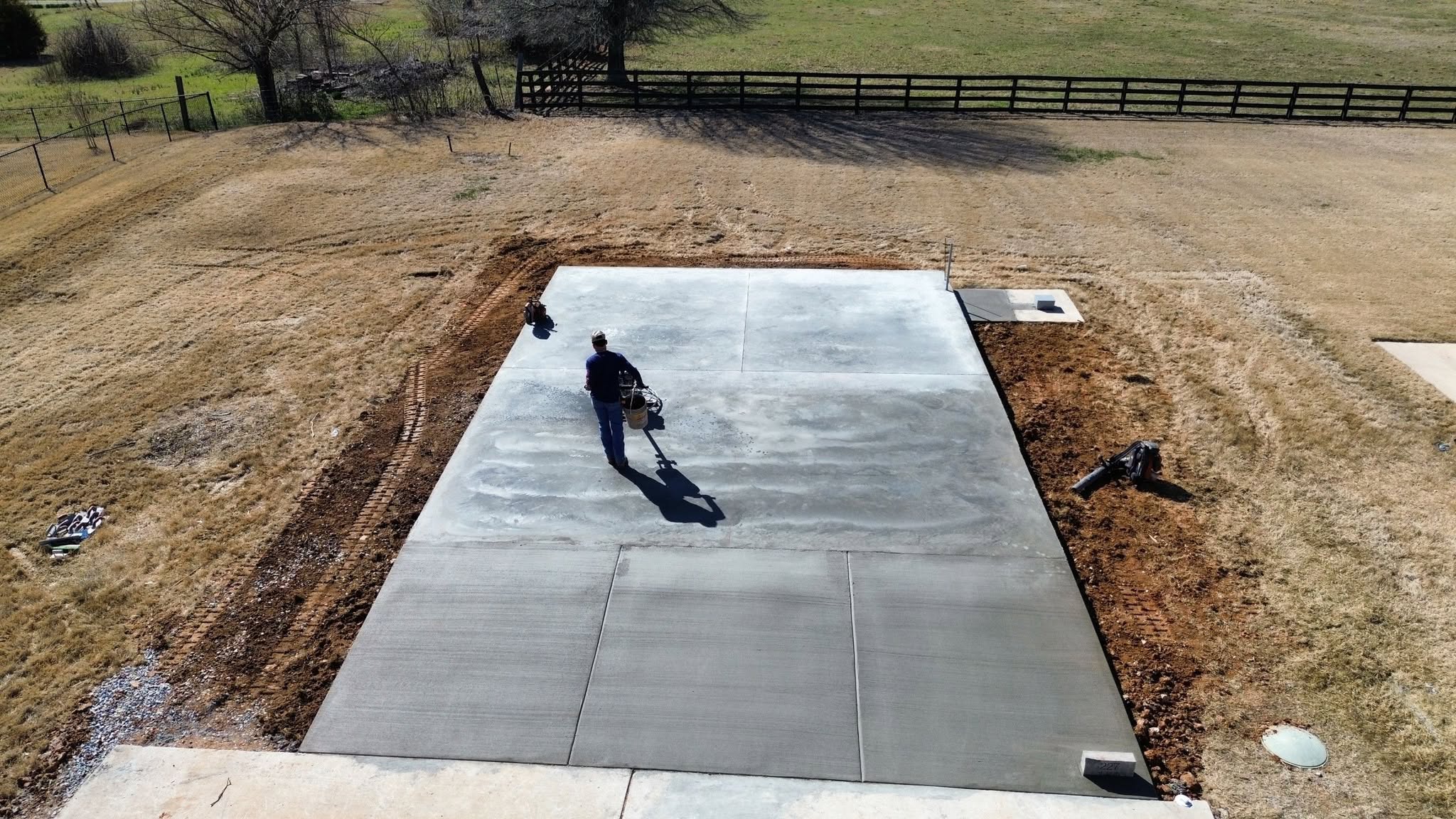 Aerial view of a Jamie's Concrete crew member finishing a large freshly poured concrete slab in North Alabama